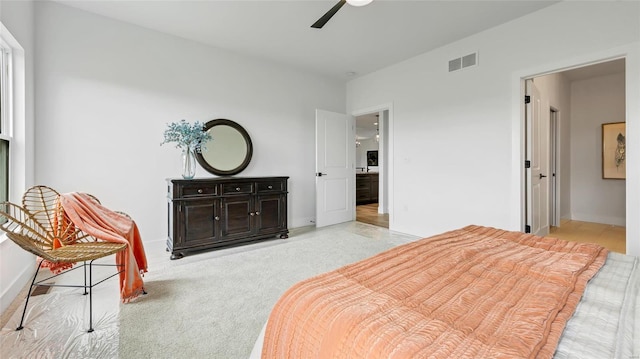 carpeted bedroom with ensuite bath and ceiling fan