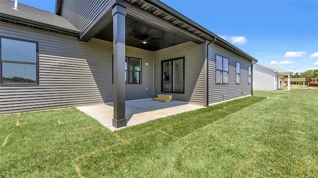 property entrance with ceiling fan, a patio area, and a yard