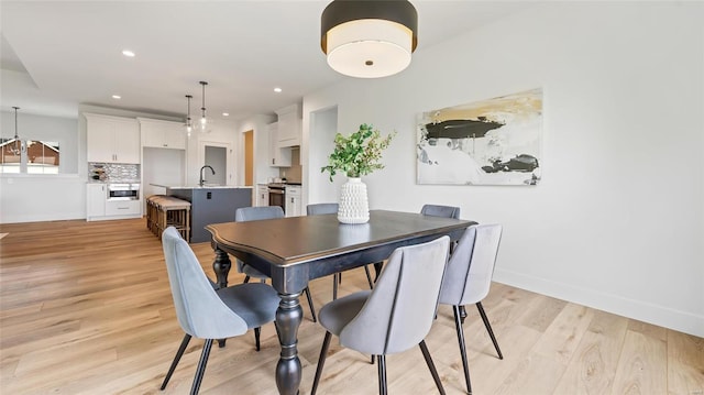 dining space with sink and light wood-type flooring