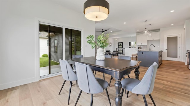 dining area with ceiling fan, sink, and light hardwood / wood-style flooring