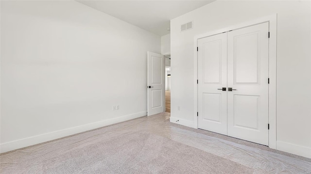 unfurnished bedroom featuring light carpet and a closet