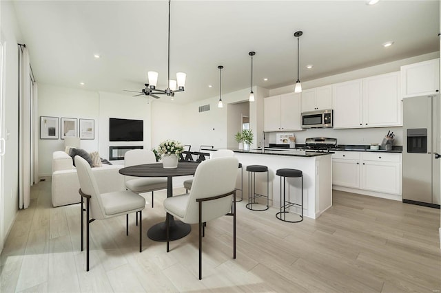 kitchen featuring white cabinetry, a center island with sink, stainless steel appliances, and light wood-type flooring