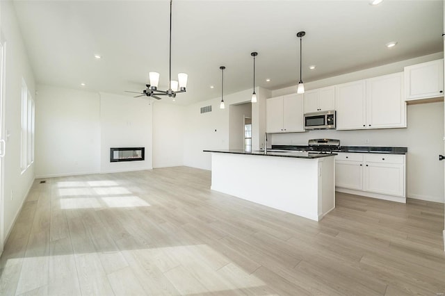 kitchen featuring stainless steel appliances, pendant lighting, a center island with sink, white cabinets, and light hardwood / wood-style floors