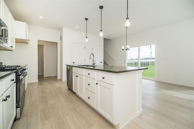 kitchen with stainless steel appliances, sink, light hardwood / wood-style flooring, white cabinets, and an island with sink