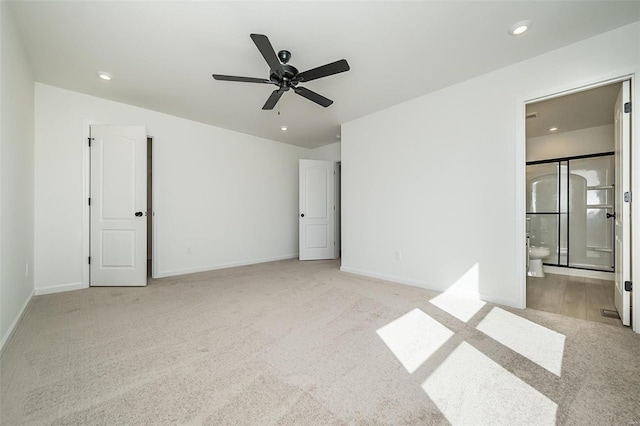 unfurnished bedroom with light colored carpet, ensuite bath, and ceiling fan