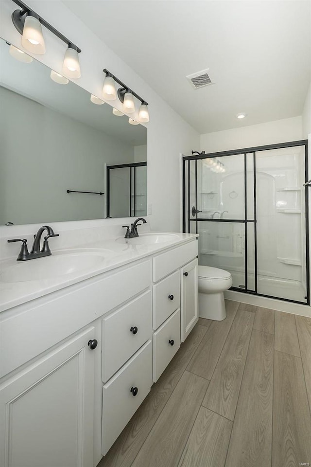 bathroom with wood-type flooring, vanity, toilet, and an enclosed shower