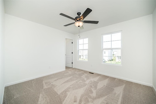 carpeted spare room featuring ceiling fan