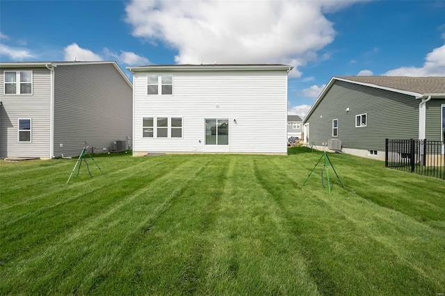 rear view of property with central air condition unit and a lawn