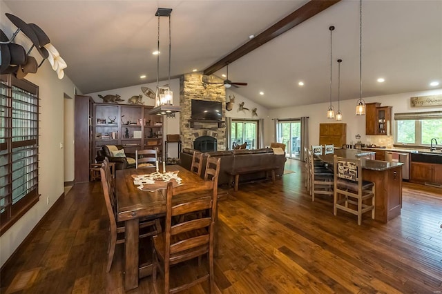 dining room with high vaulted ceiling, dark hardwood / wood-style flooring, ceiling fan, and a stone fireplace