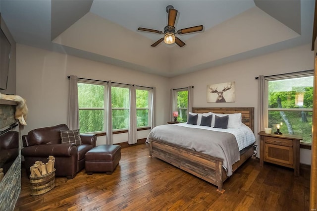 bedroom featuring ceiling fan, a tray ceiling, and dark wood-type flooring