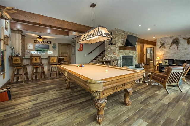 playroom featuring beamed ceiling, ceiling fan, a stone fireplace, billiards, and hardwood / wood-style flooring