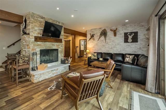 living room featuring wood-type flooring and a stone fireplace