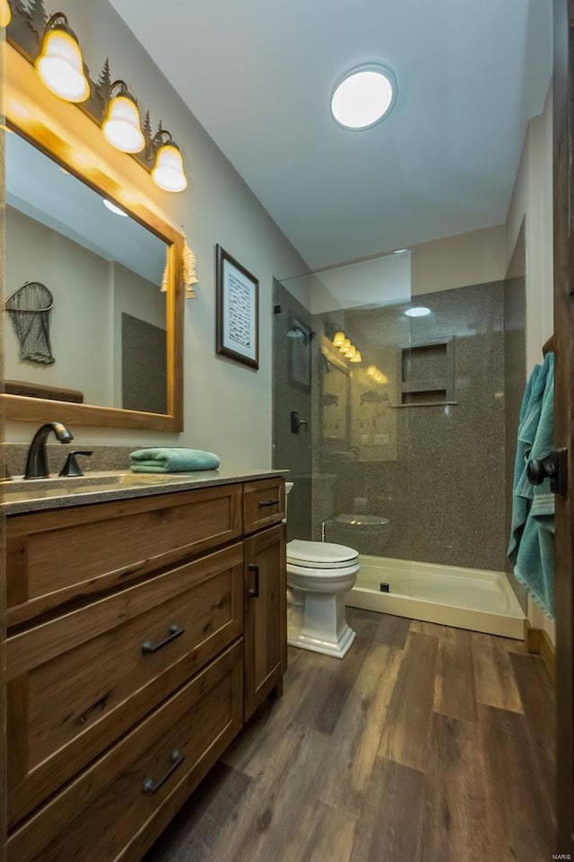 bathroom featuring a shower with door, hardwood / wood-style flooring, vanity, and toilet