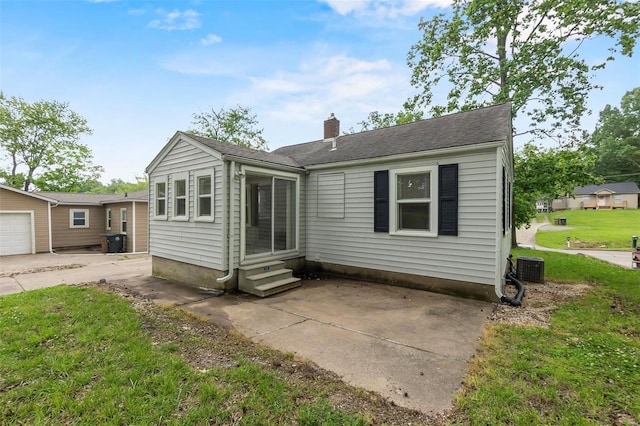 rear view of house with a garage, a yard, and central air condition unit