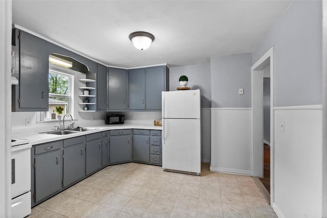 kitchen with stove, light wood-type flooring, gray cabinets, white fridge, and sink