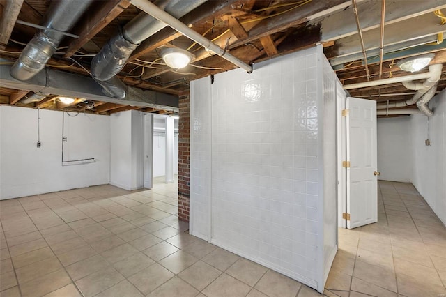 basement featuring brick wall and light tile floors