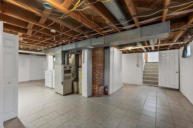 basement with tile flooring, heating utilities, brick wall, and washing machine and clothes dryer