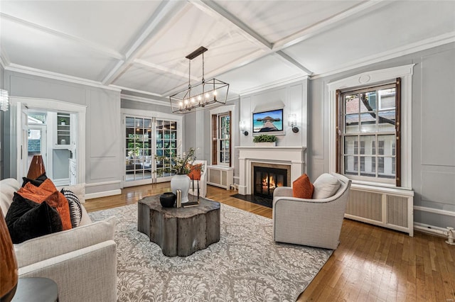 living room with a chandelier, wood-type flooring, coffered ceiling, and radiator heating unit