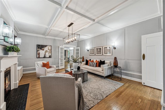 living room with french doors, a notable chandelier, coffered ceiling, and light hardwood / wood-style flooring