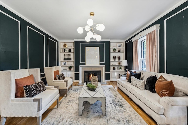 living room featuring hardwood / wood-style flooring, built in features, ornamental molding, and a chandelier