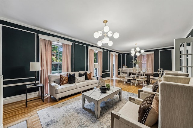 living room with wood-type flooring, crown molding, and an inviting chandelier