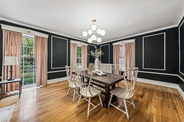 dining space with crown molding, a chandelier, and light hardwood / wood-style flooring