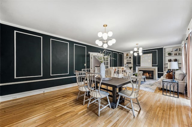 dining room featuring built in shelves, a notable chandelier, crown molding, and hardwood / wood-style floors