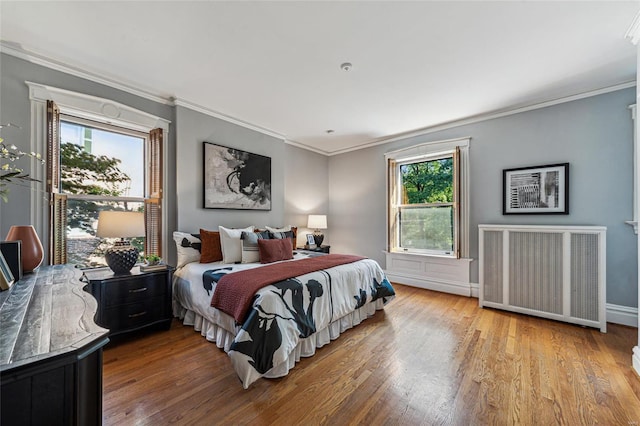 bedroom with radiator heating unit, crown molding, and light hardwood / wood-style flooring