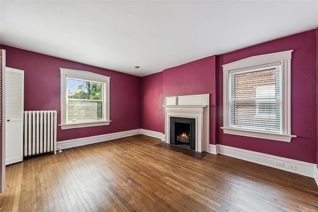 unfurnished living room featuring wood-type flooring and radiator heating unit