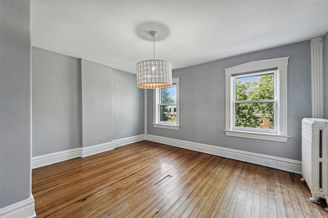 unfurnished dining area featuring radiator, a healthy amount of sunlight, and hardwood / wood-style flooring