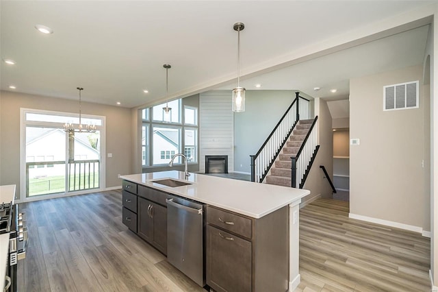 kitchen with a center island with sink, pendant lighting, sink, and appliances with stainless steel finishes