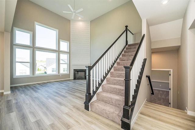 stairway featuring a wealth of natural light, hardwood / wood-style floors, a towering ceiling, and ceiling fan