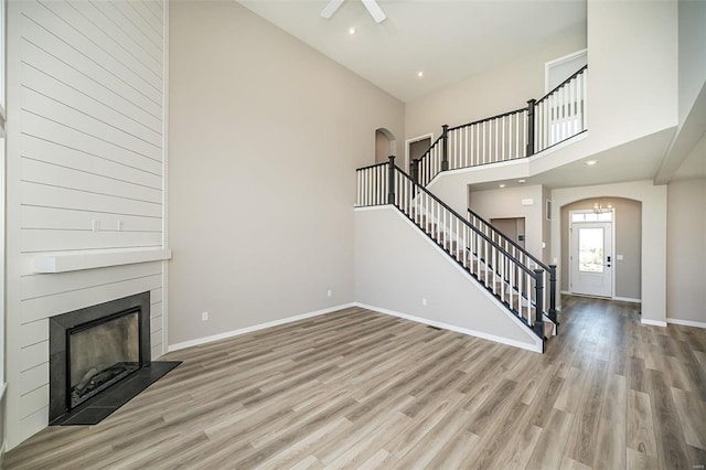 unfurnished living room with a towering ceiling and light wood-type flooring