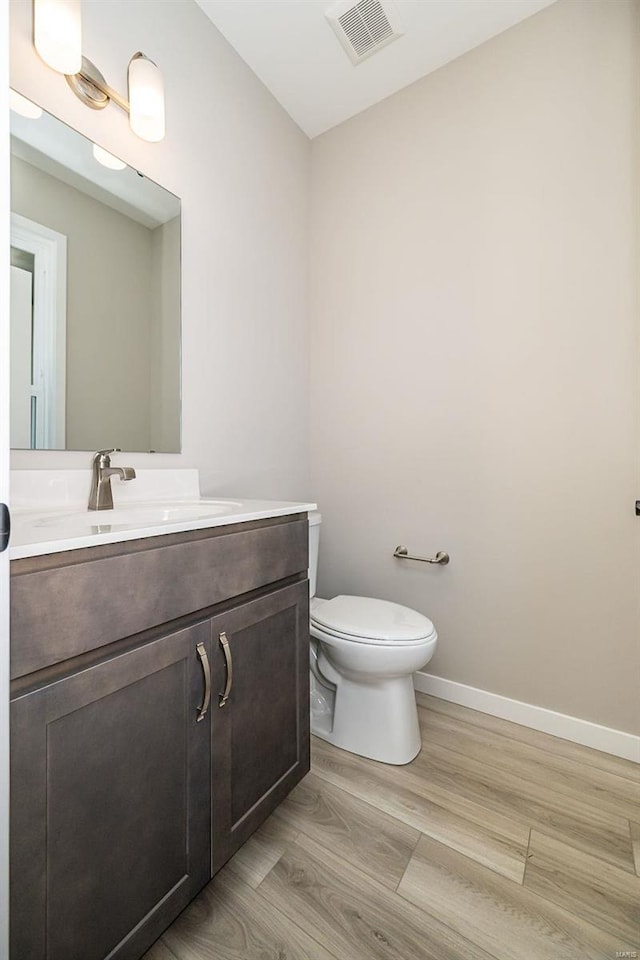 bathroom featuring wood-type flooring, vanity, and toilet