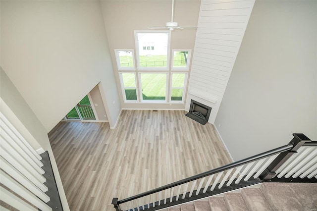 unfurnished living room with ceiling fan, light hardwood / wood-style flooring, and a towering ceiling