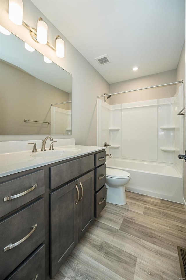 full bathroom with bathing tub / shower combination, vanity, wood-type flooring, and toilet