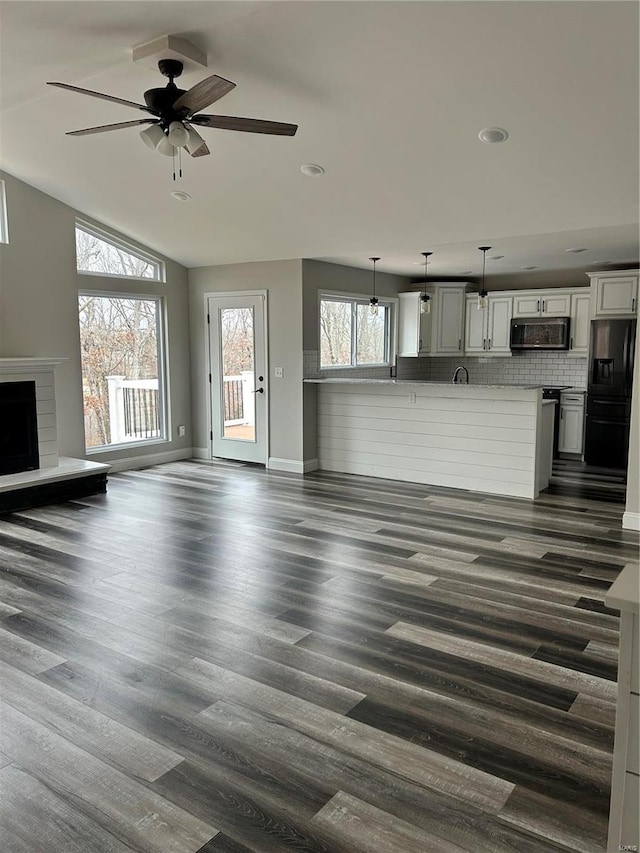 unfurnished living room with ceiling fan, lofted ceiling, and dark hardwood / wood-style flooring