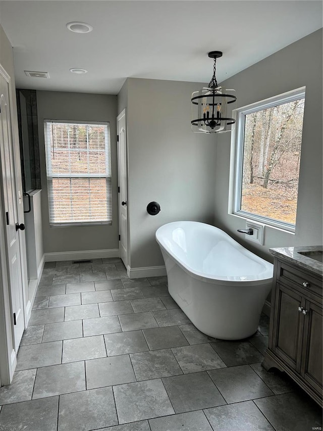 bathroom featuring a notable chandelier, a bathing tub, and vanity