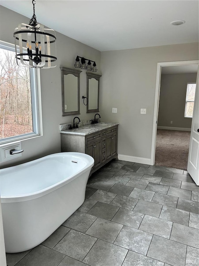 bathroom featuring vanity, an inviting chandelier, and a bathtub