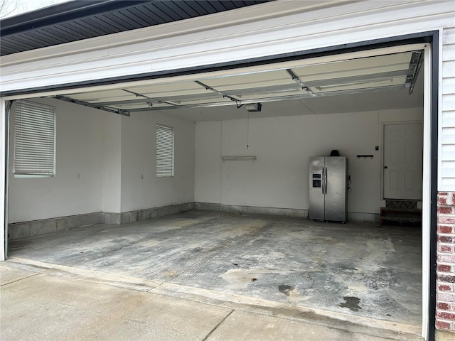 garage with a garage door opener and stainless steel refrigerator with ice dispenser