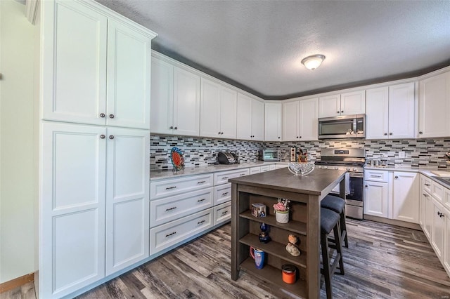 kitchen with white cabinetry, dark hardwood / wood-style flooring, stainless steel appliances, and a textured ceiling