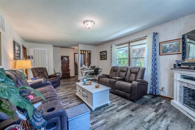 living room with a fireplace, a textured ceiling, and dark wood-type flooring