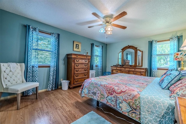 bedroom with hardwood / wood-style flooring, ceiling fan, and a textured ceiling