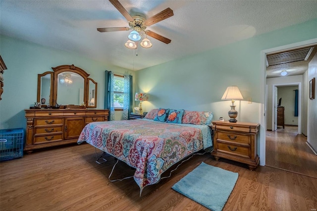 bedroom with ceiling fan, wood-type flooring, and a textured ceiling