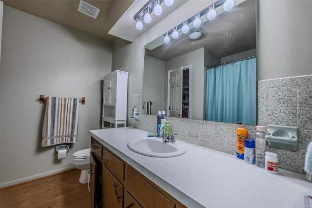 bathroom featuring a textured ceiling, vanity, hardwood / wood-style flooring, and toilet