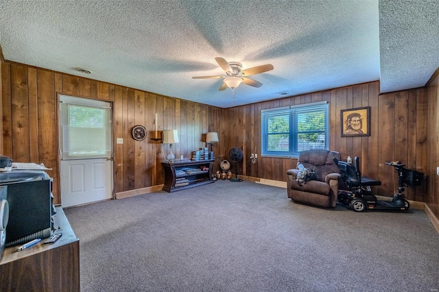 misc room with carpet flooring, a textured ceiling, ceiling fan, and wood walls