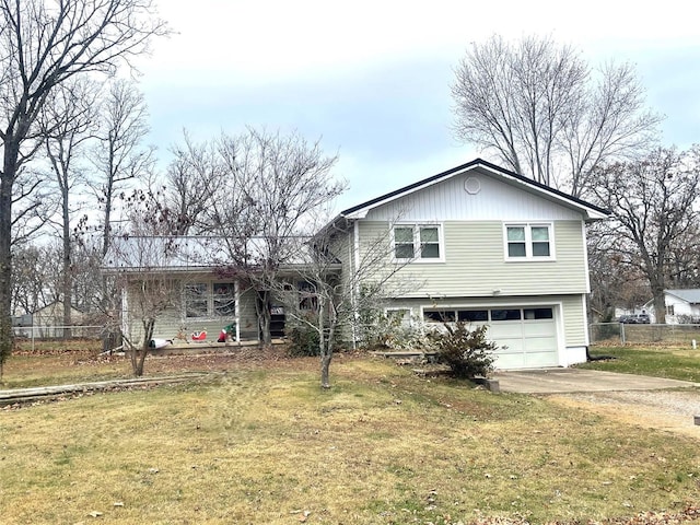 tri-level home with a garage, a front yard, driveway, and fence