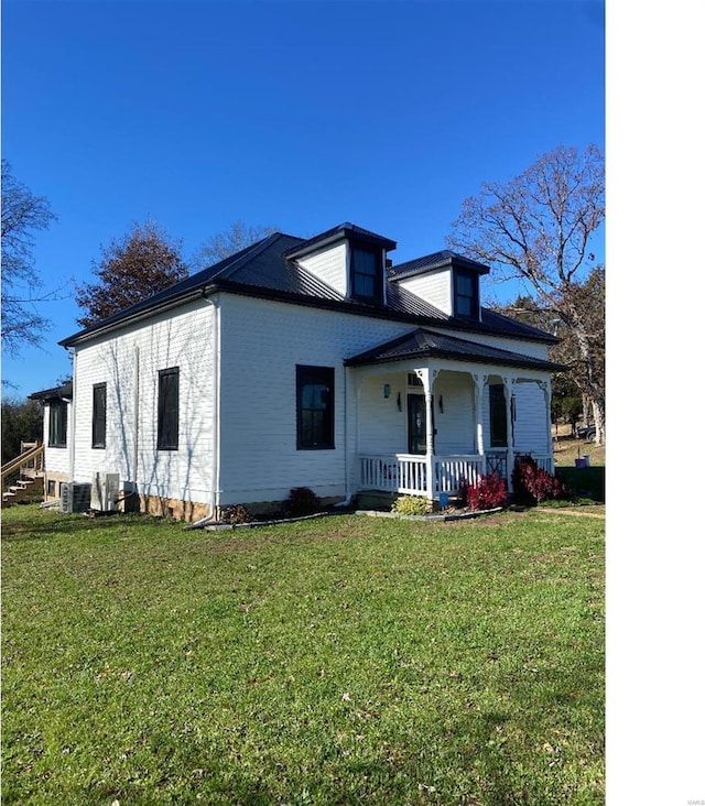 view of front of property featuring central AC unit, covered porch, and a front yard