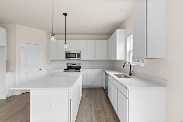 kitchen featuring a kitchen island, appliances with stainless steel finishes, white cabinetry, and hardwood / wood-style floors