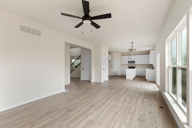 unfurnished living room with ceiling fan, sink, and light wood-type flooring